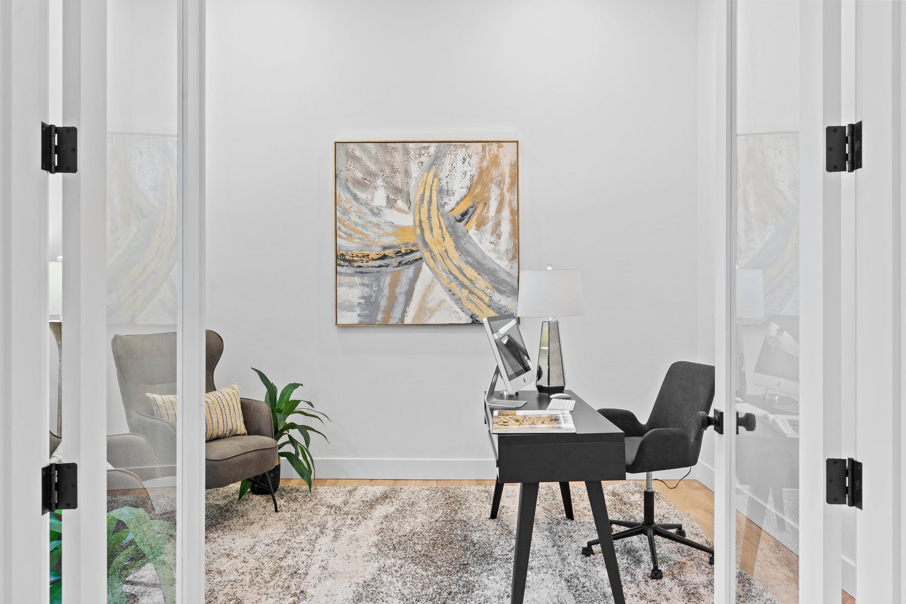 A home office with a desk and chair and a painting on the wall.