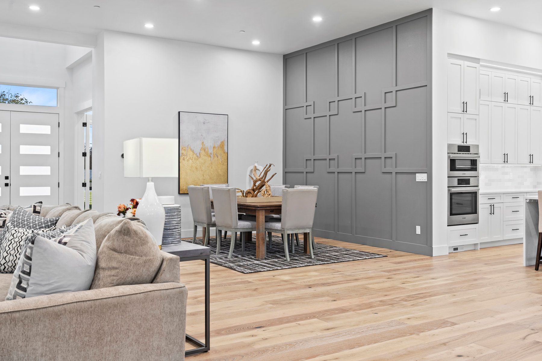 A living room and dining room in a house with hardwood floors and a gray wall.