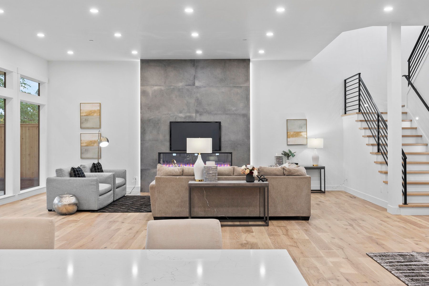 A living room with a couch , chairs , stairs and a television.