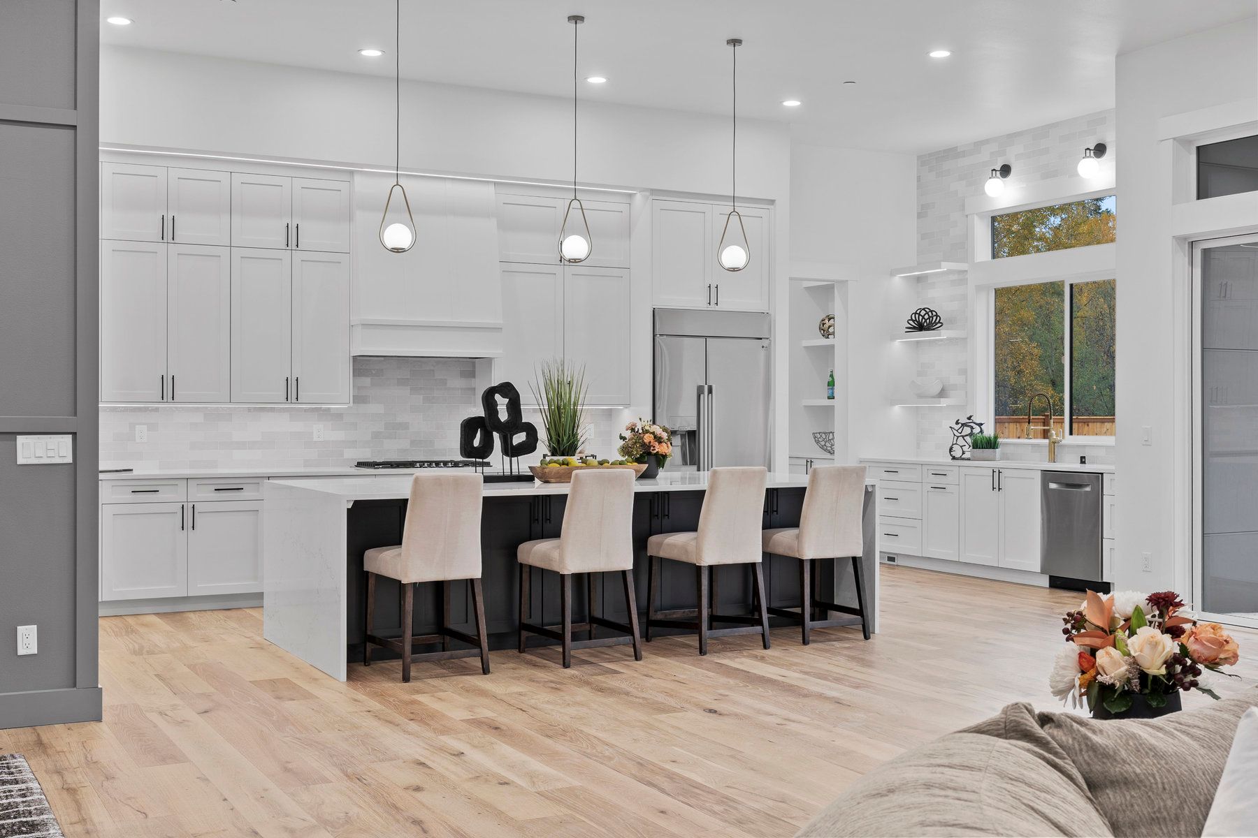 A kitchen with white cabinets , stainless steel appliances , hardwood floors and a large island.