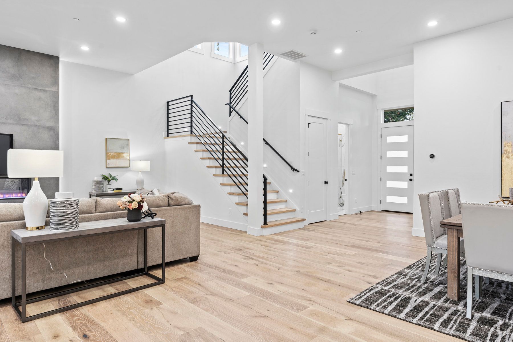 A living room with a couch , table , chairs and stairs.