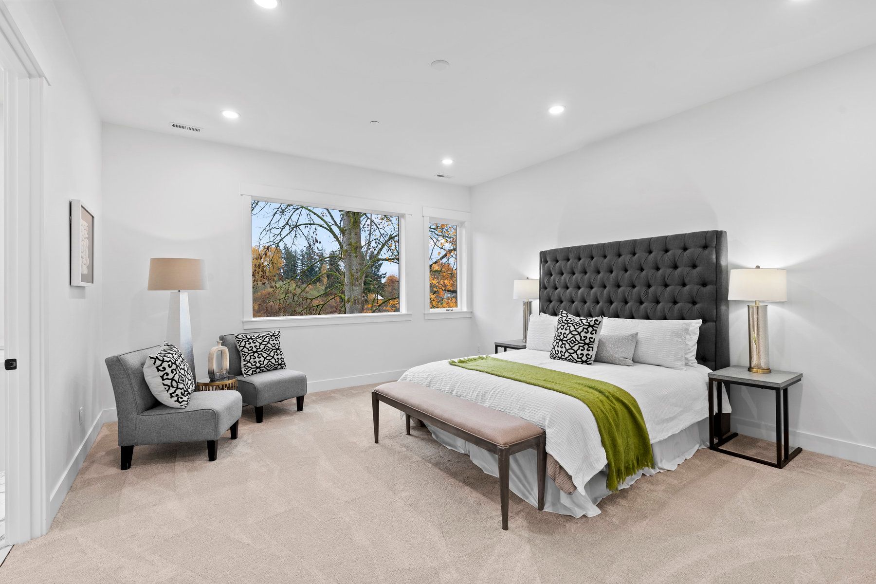 A bedroom with a bed , chairs , lamps and a bench.