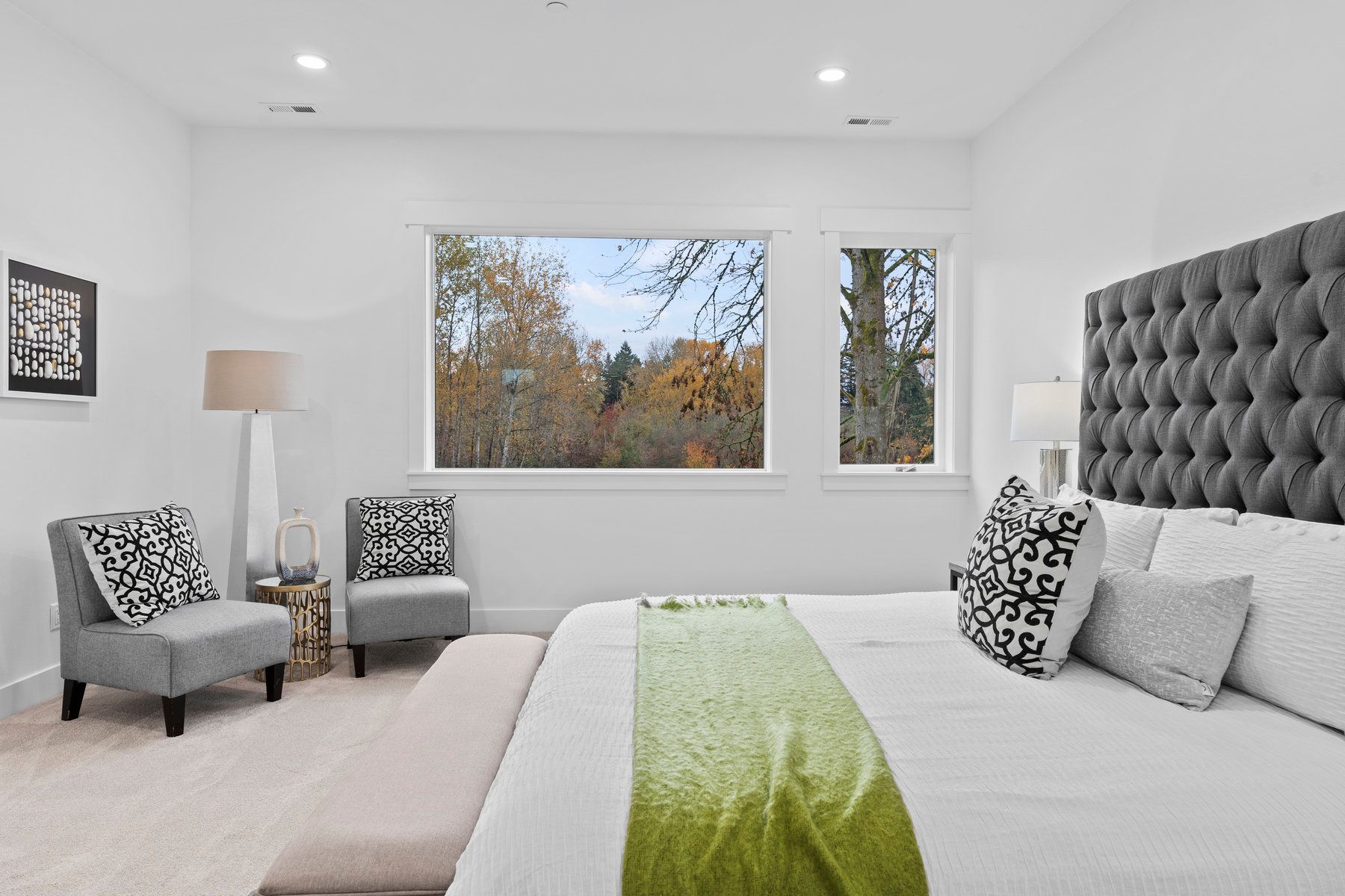A bedroom with a bed , chairs , and a large window.