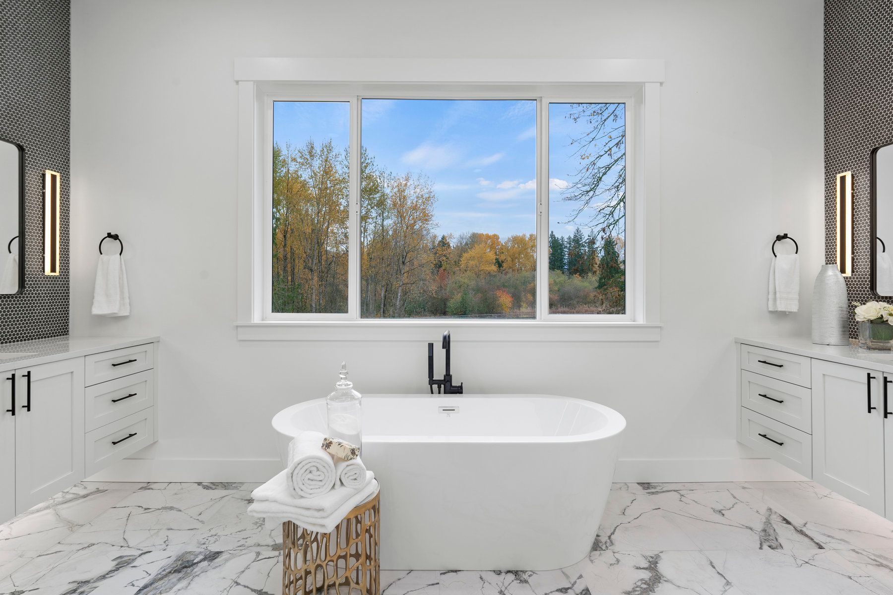 A bathroom with two sinks , a tub , and a large window.