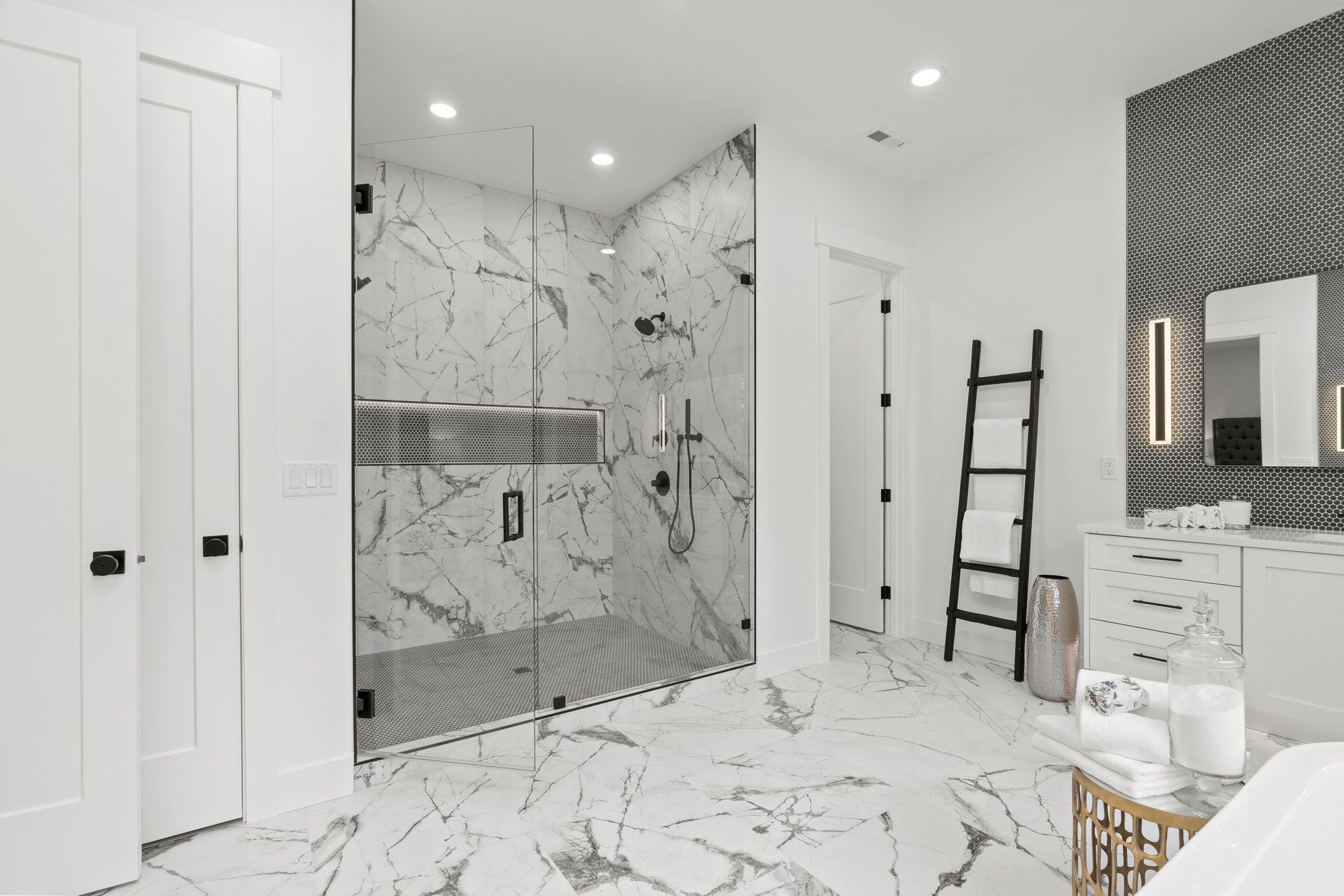 A bathroom with a walk in shower , sink , mirror and ladder.