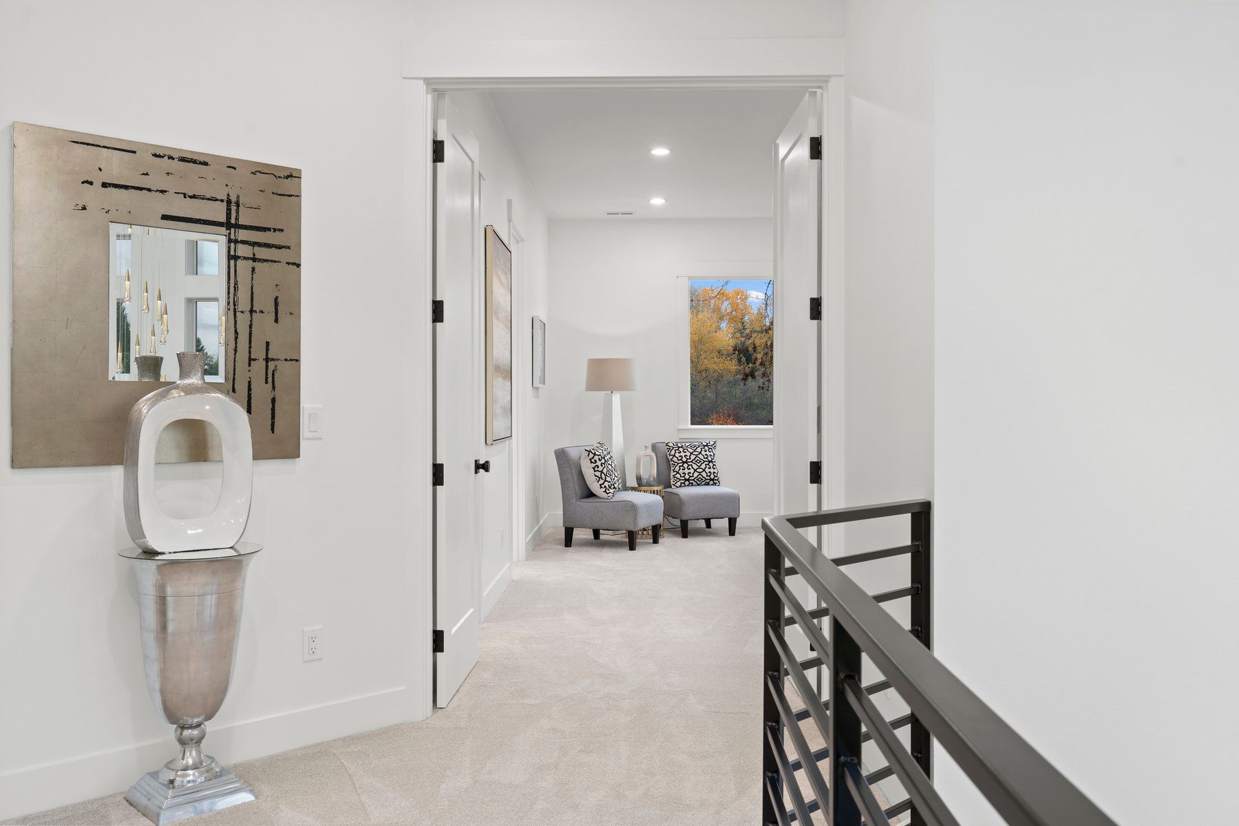 A hallway leading to a living room with chairs and a vase.