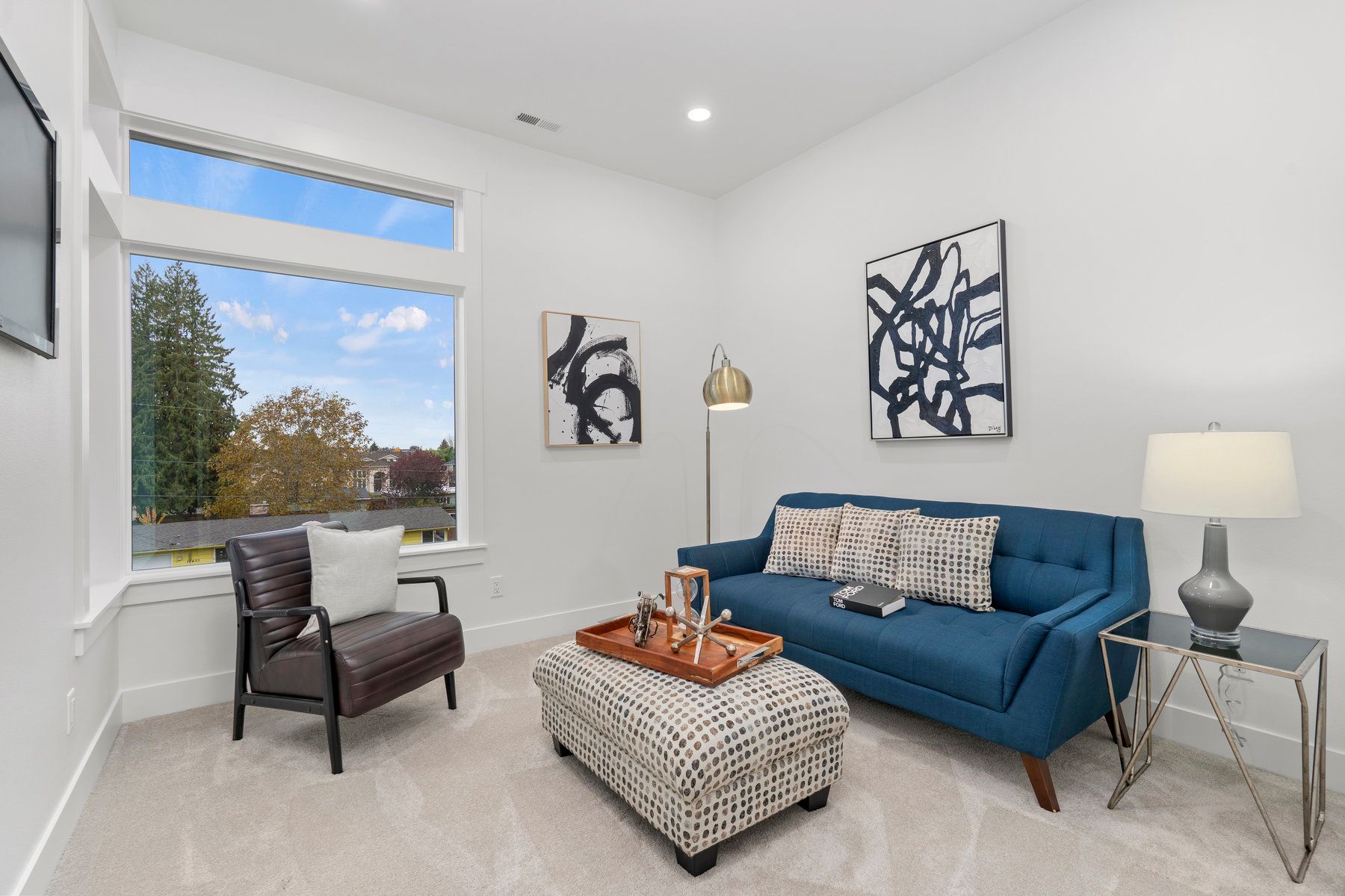 A living room with a blue couch , ottoman , chair and television.