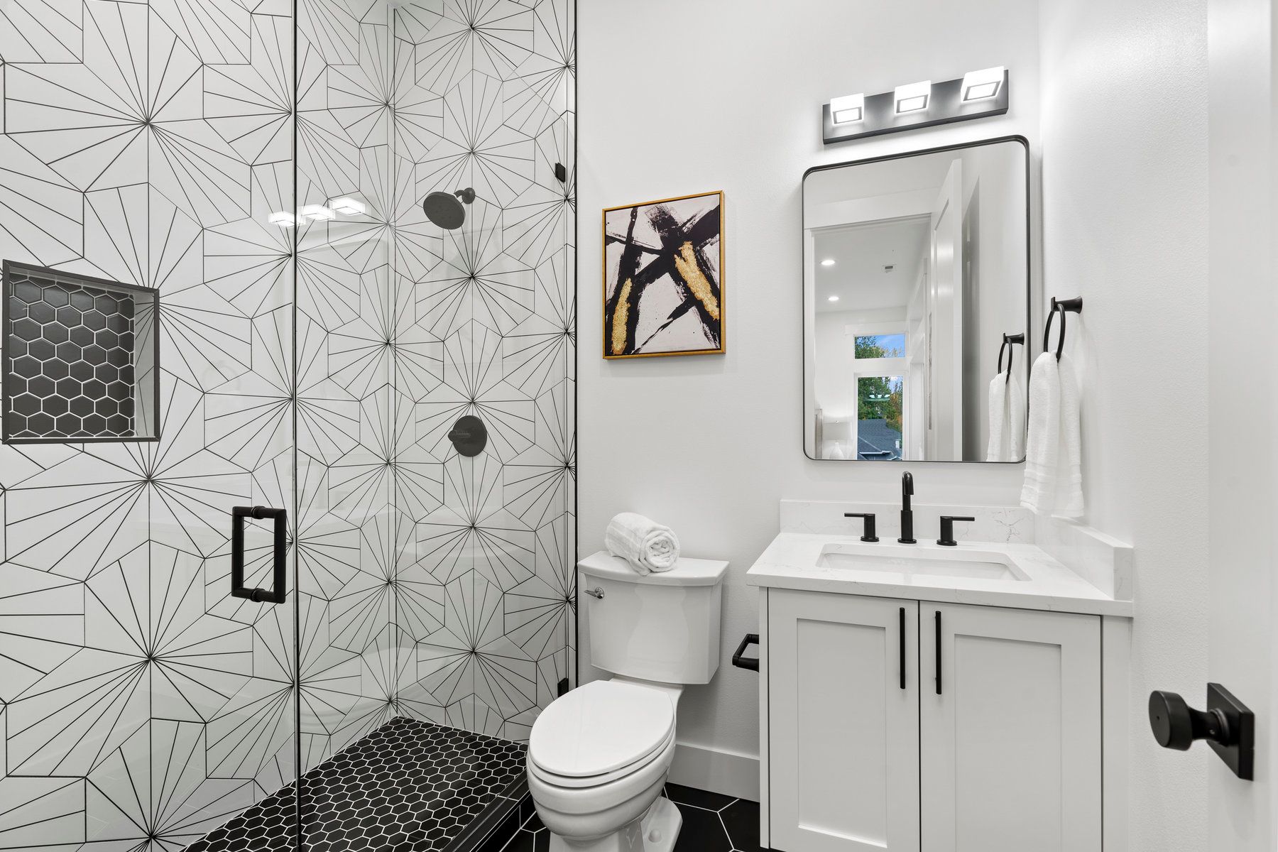 A bathroom with a toilet , sink , shower and mirror.