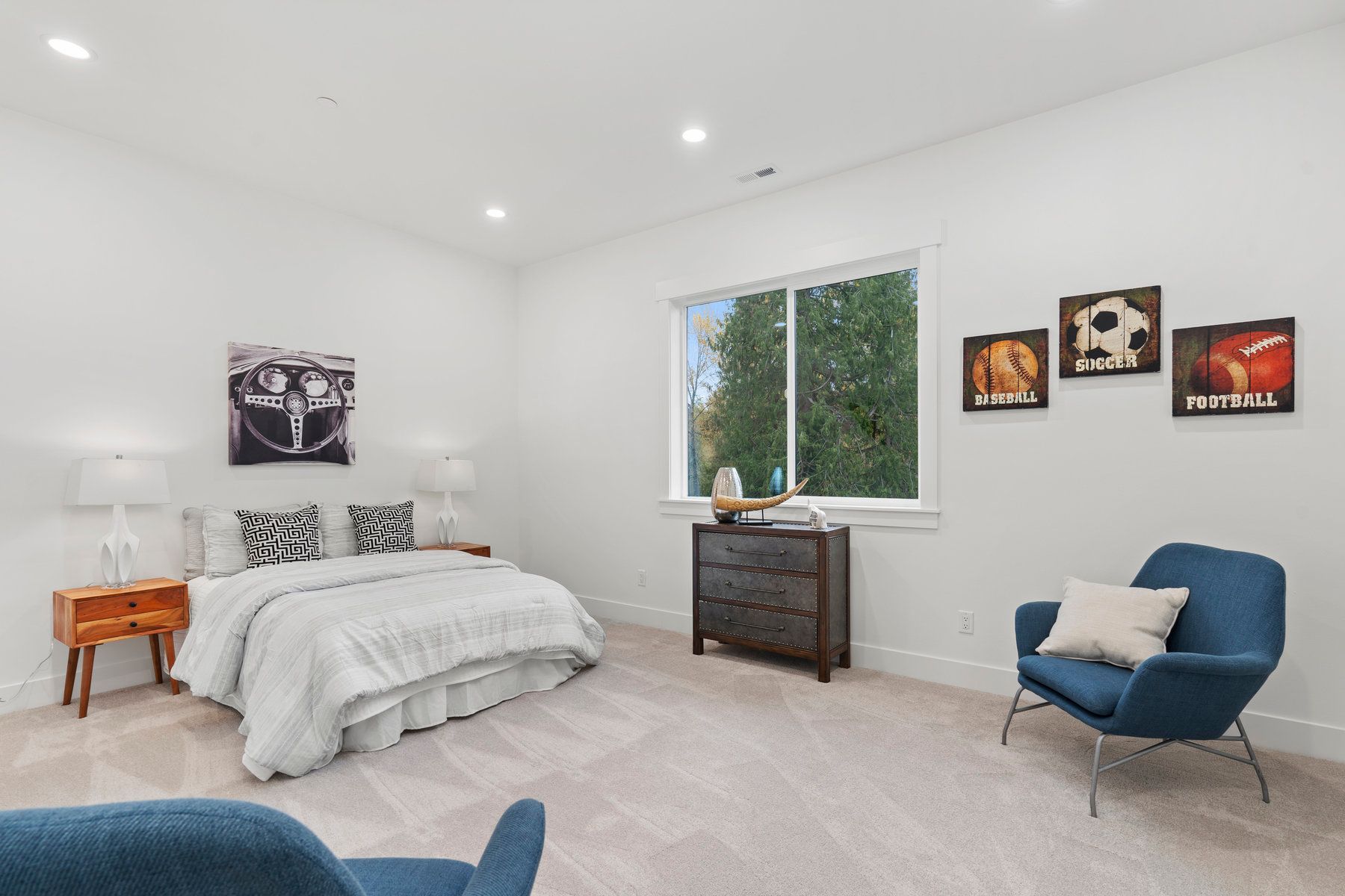 A bedroom with a bed , chair , dresser and window.