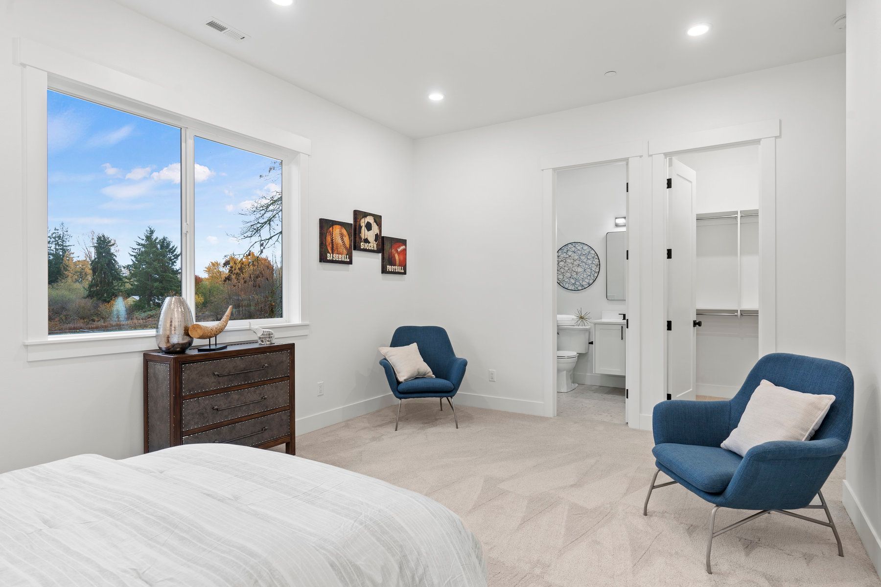 A bedroom with a bed , chair , dresser and window.
