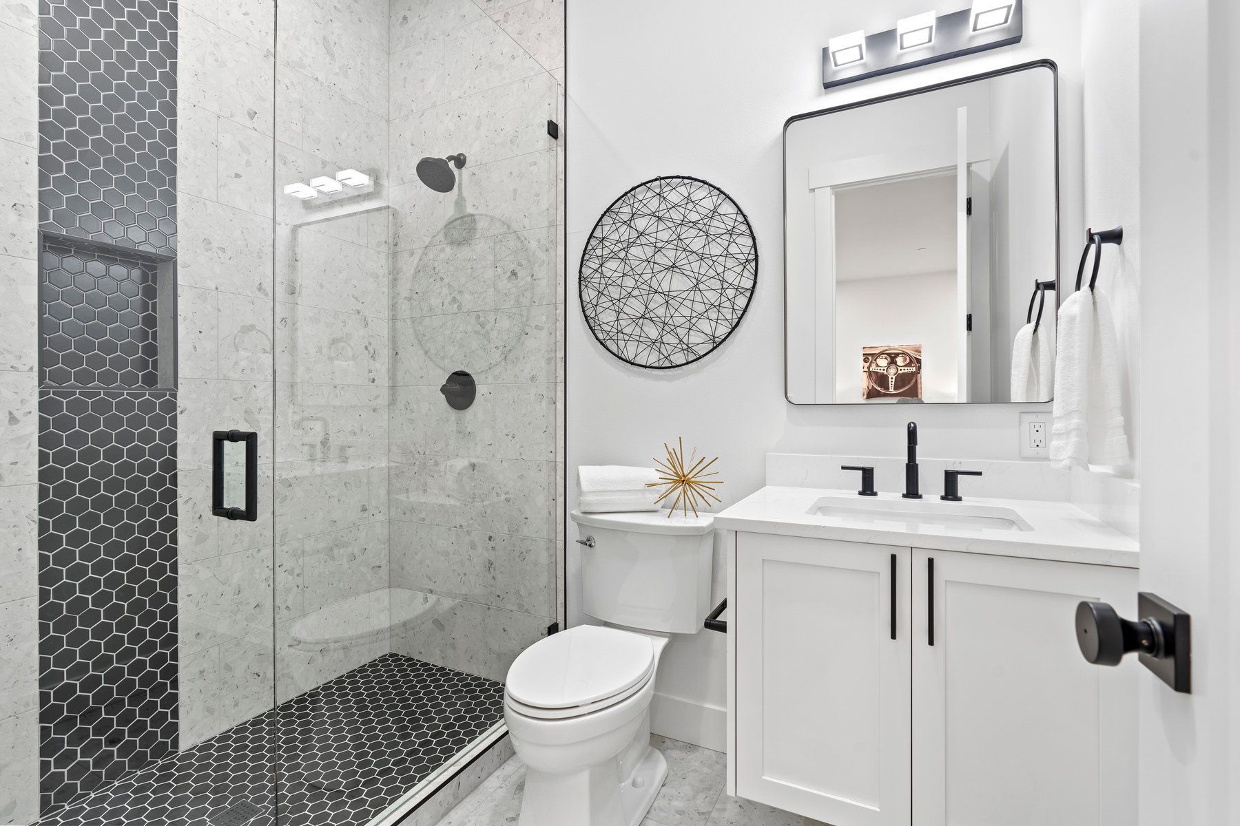 A bathroom with a toilet , sink , mirror and walk in shower.