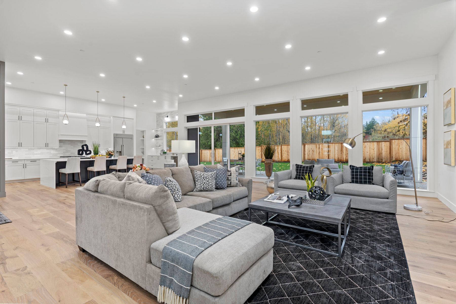 A living room with a couch , two couches , a coffee table , and a rug.