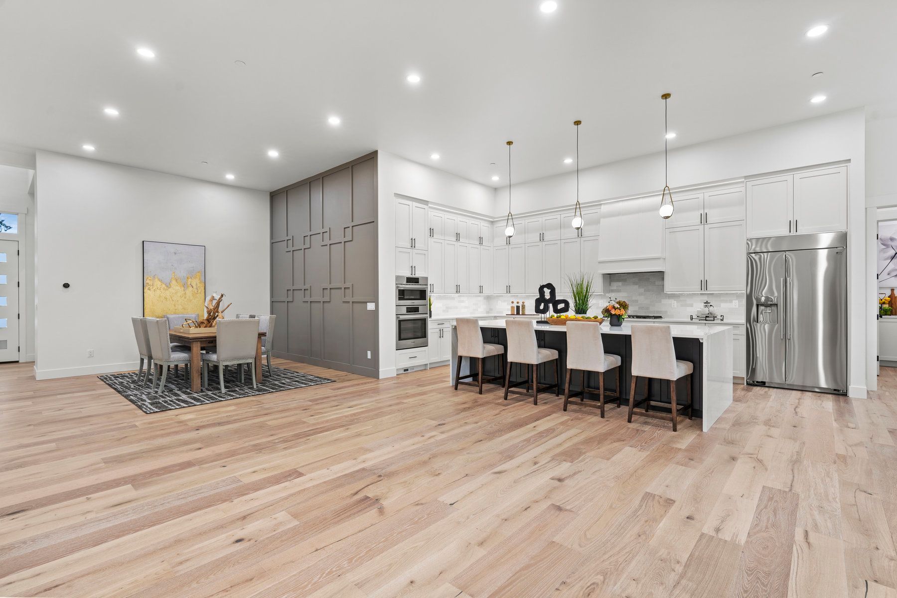 A kitchen and dining room in a house with hardwood floors and white cabinets.
