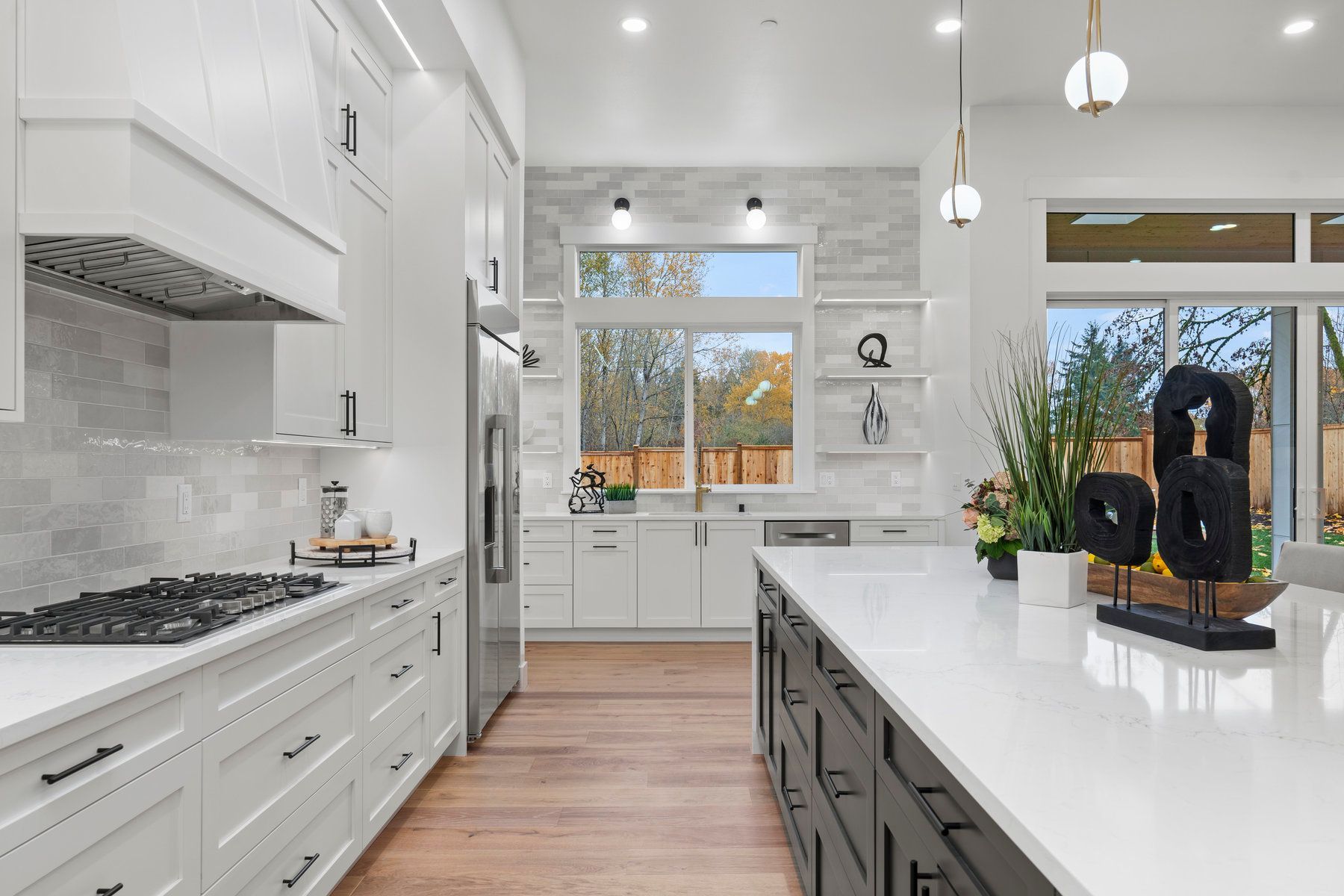 A kitchen with white cabinets , stainless steel appliances , and a large island.
