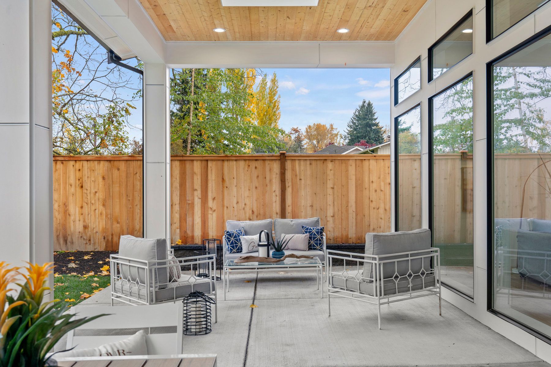 A patio with a couch and chairs and a wooden fence in the background.