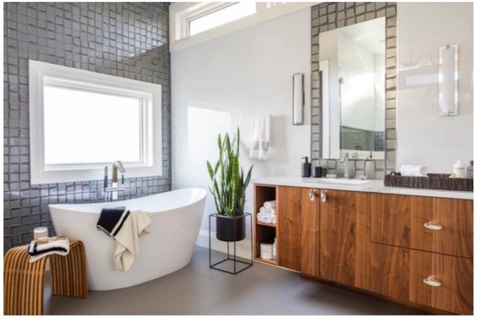 A bathroom with a tub , sink , mirror and window.