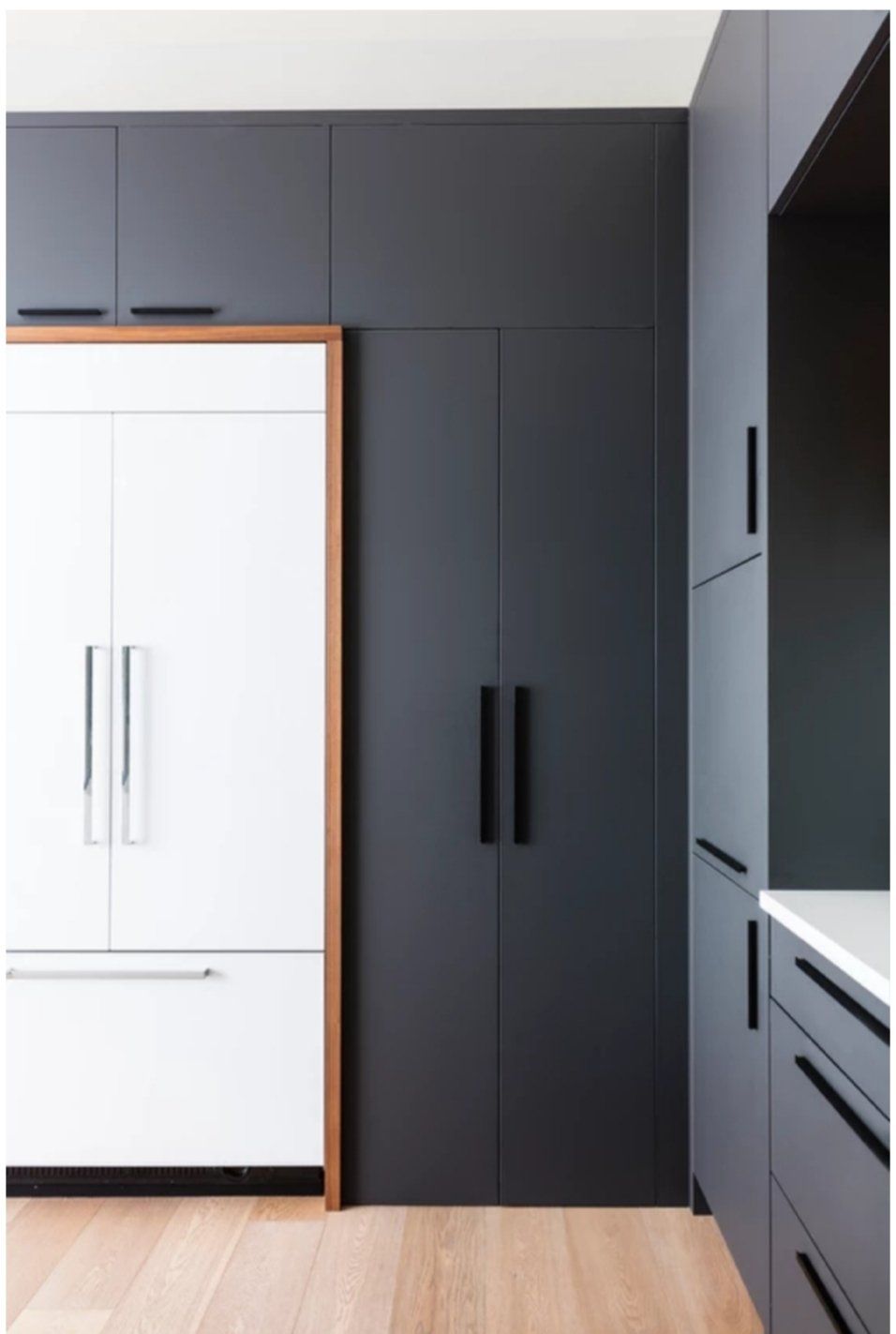 A kitchen with black and white cabinets and a refrigerator.
