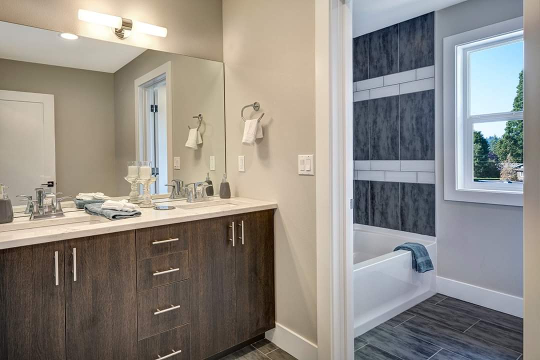 A bathroom with two sinks , a mirror , a tub and a window.