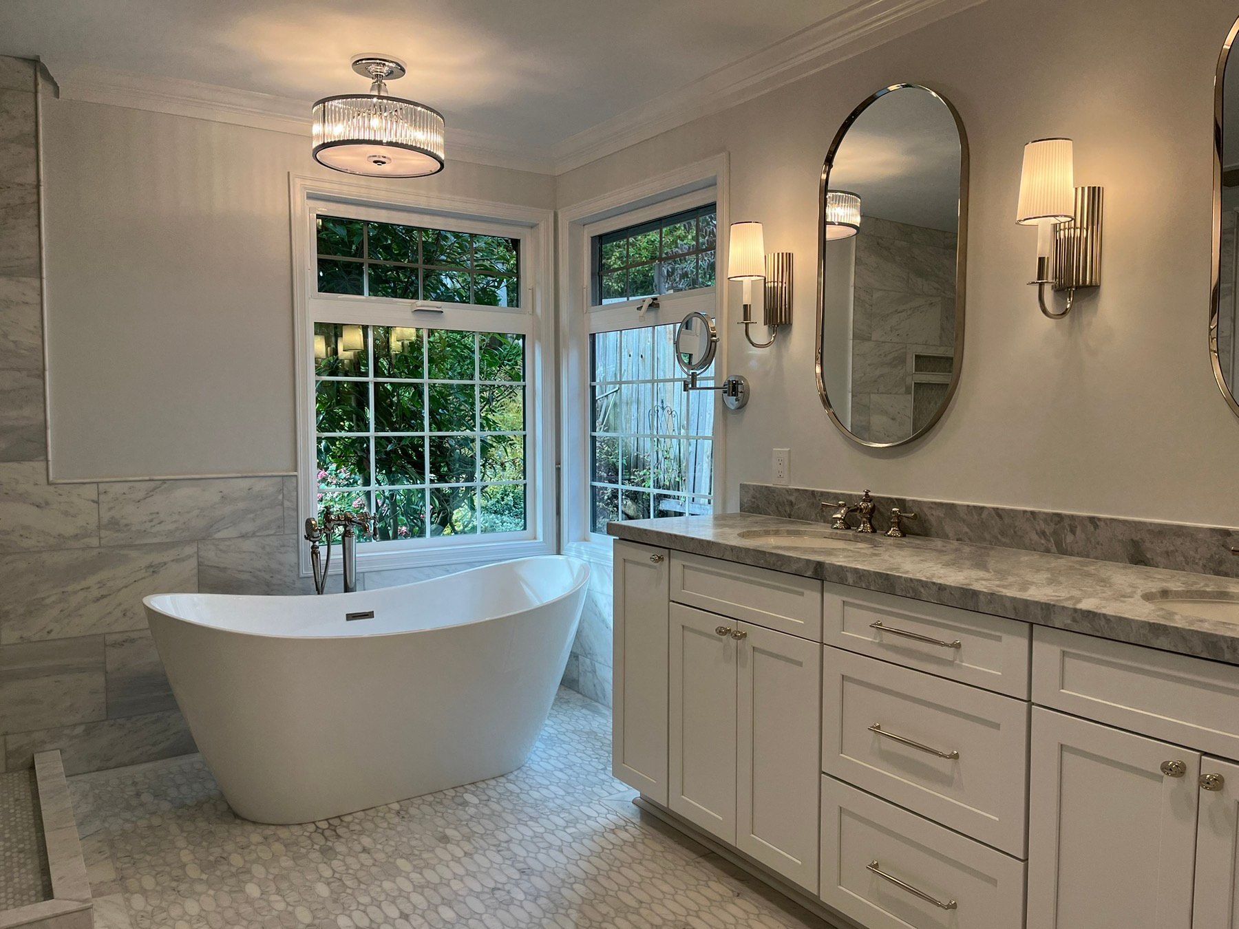 A bathroom with a tub , sinks , mirrors and a window.