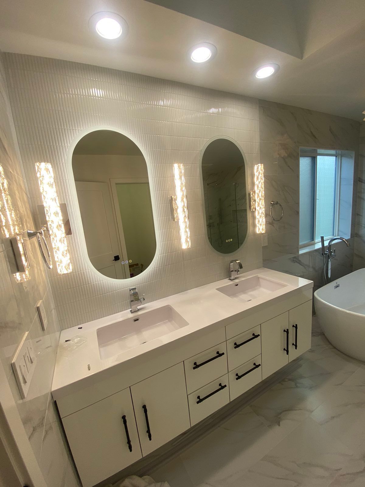 A bathroom with two sinks , a bathtub and a mirror.