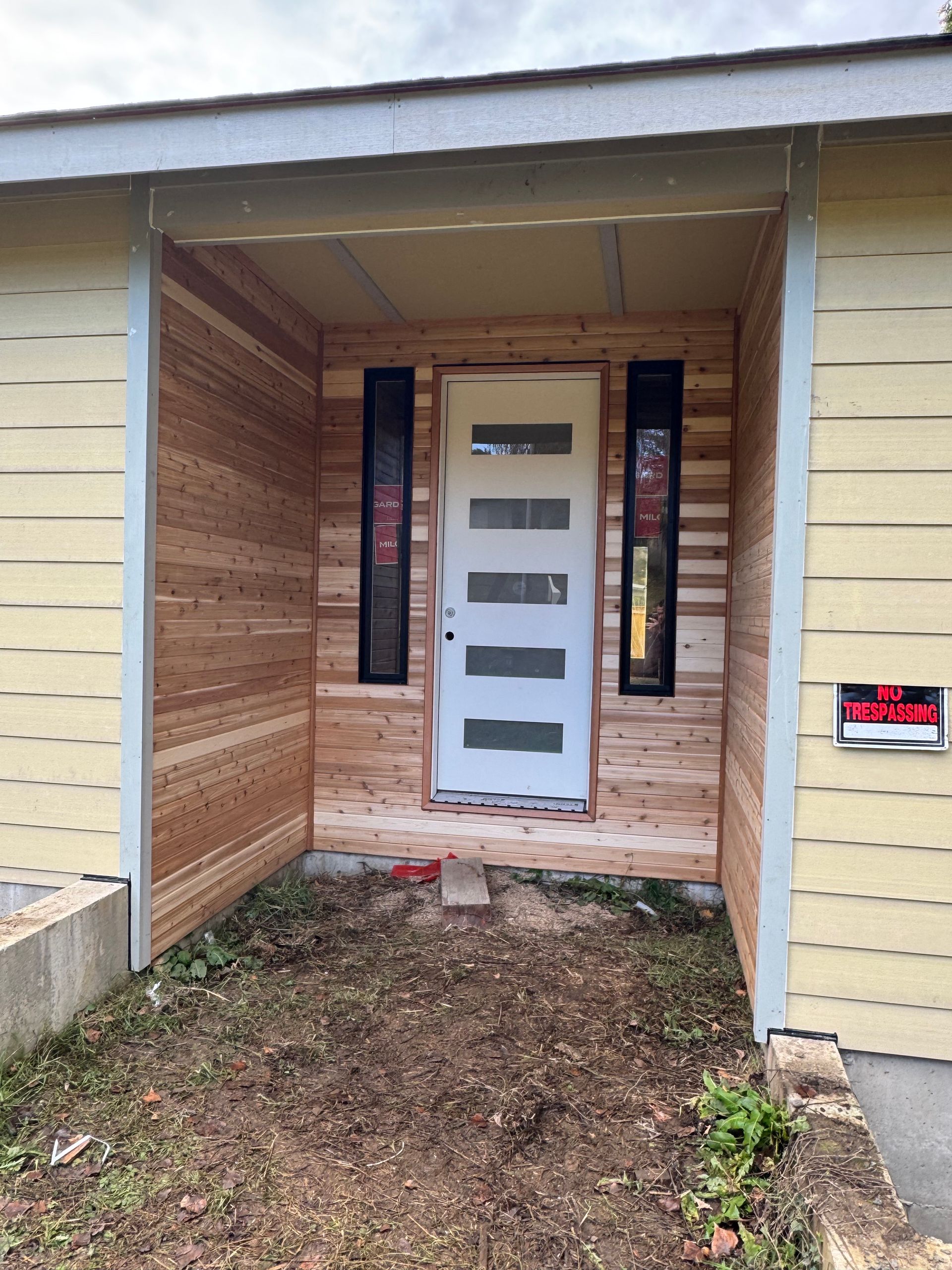 The front of a house with a white door and wooden siding.