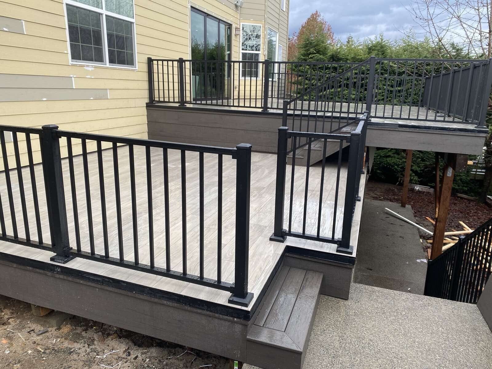 A large deck with a black railing and stairs leading up to it.