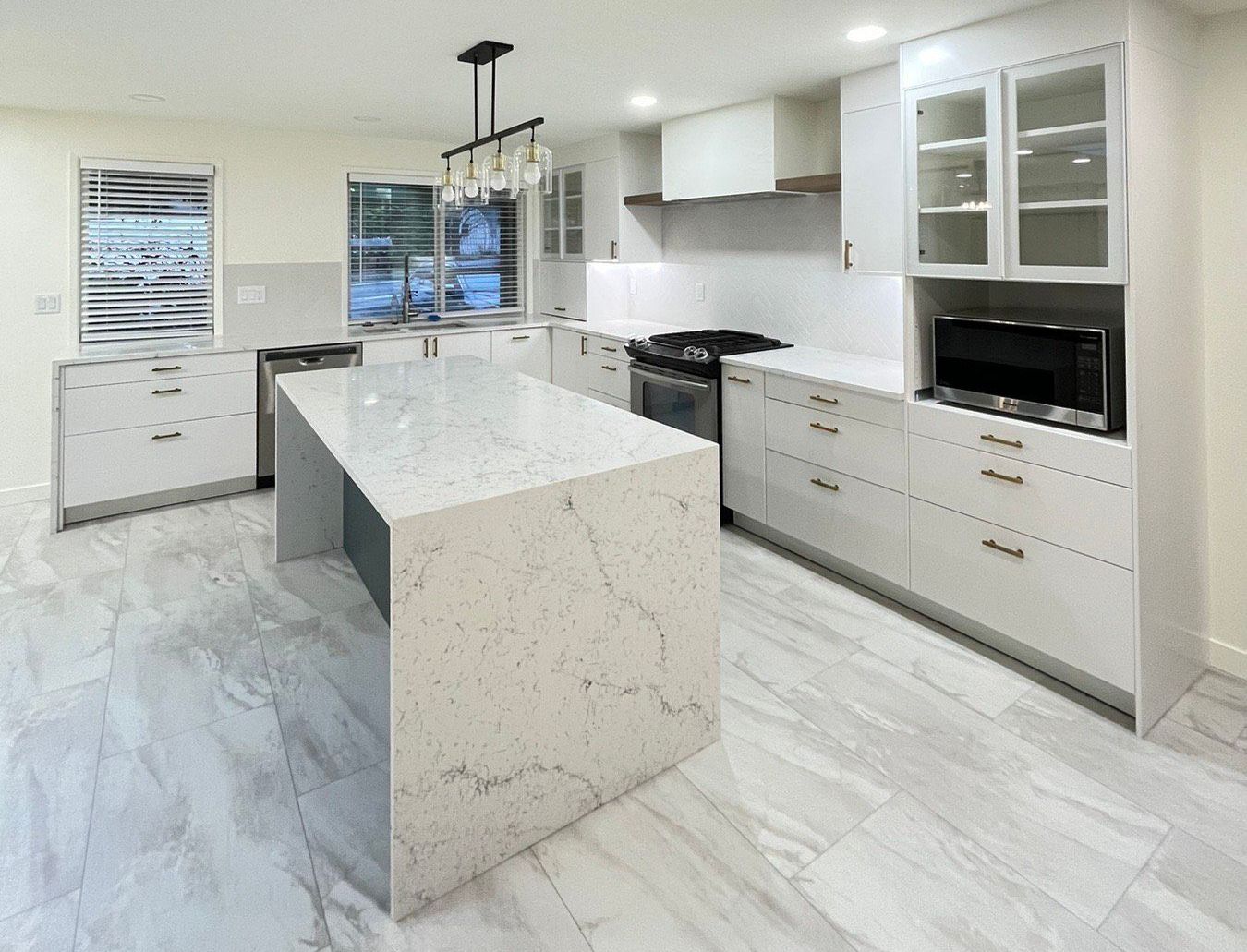 A kitchen with white cabinets and a large island in the middle