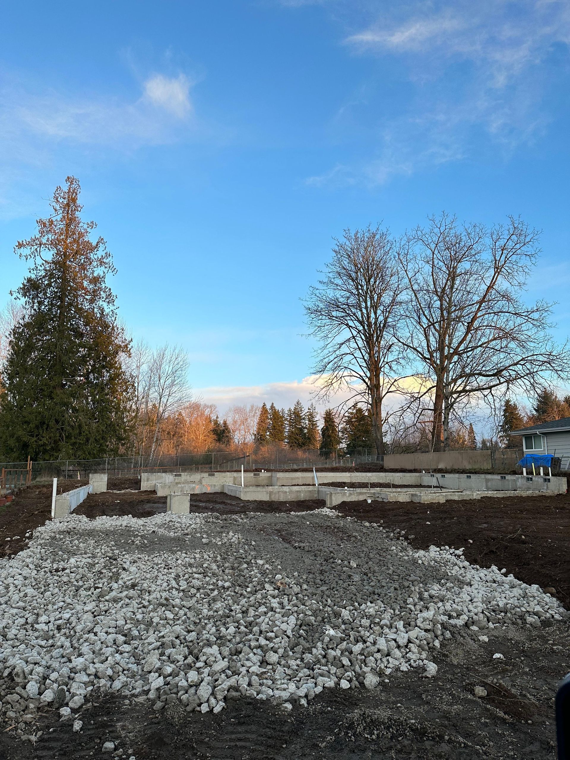 A construction site with a lot of gravel and trees in the background.