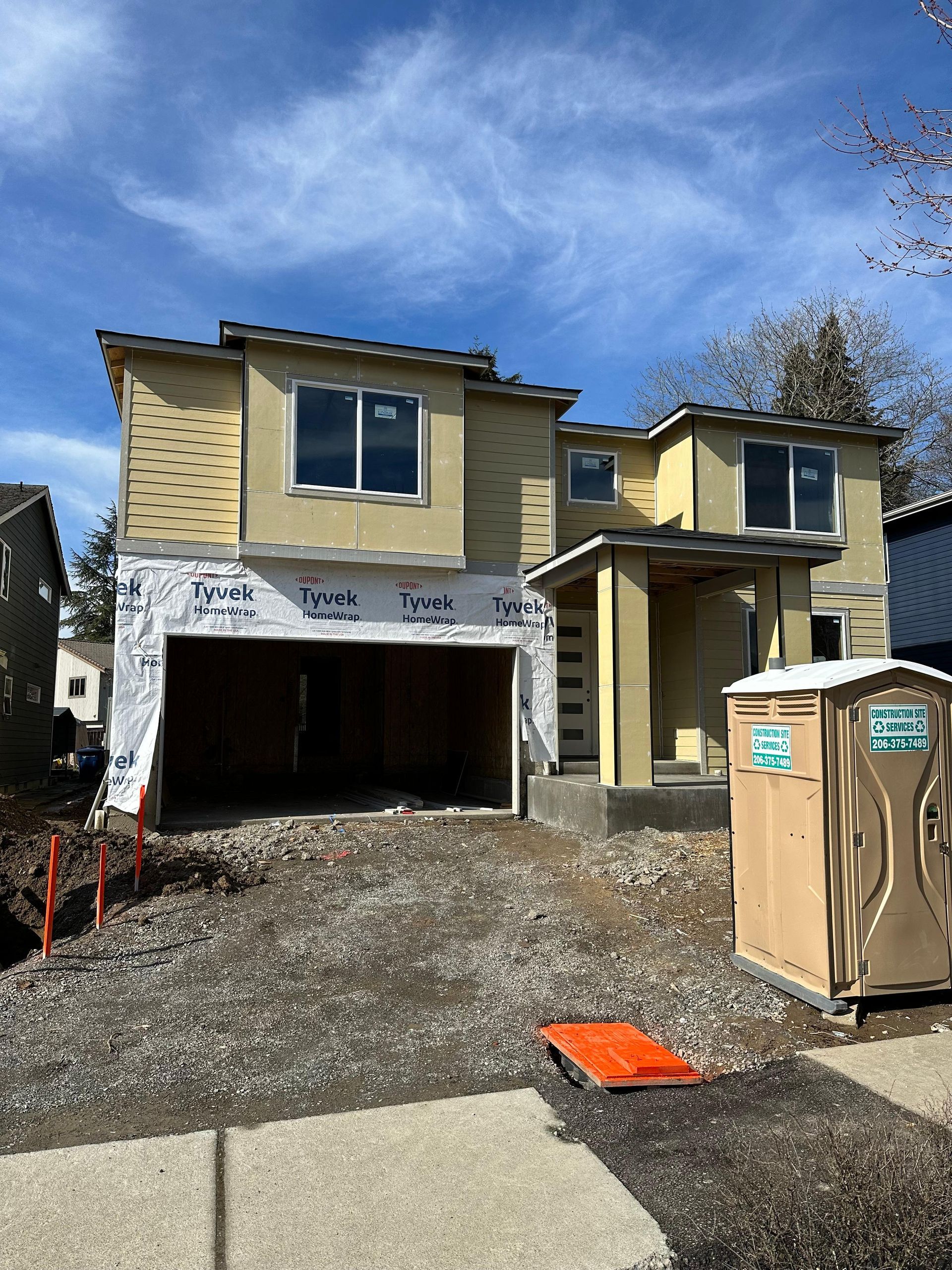 A house under construction with a portable toilet in front of it