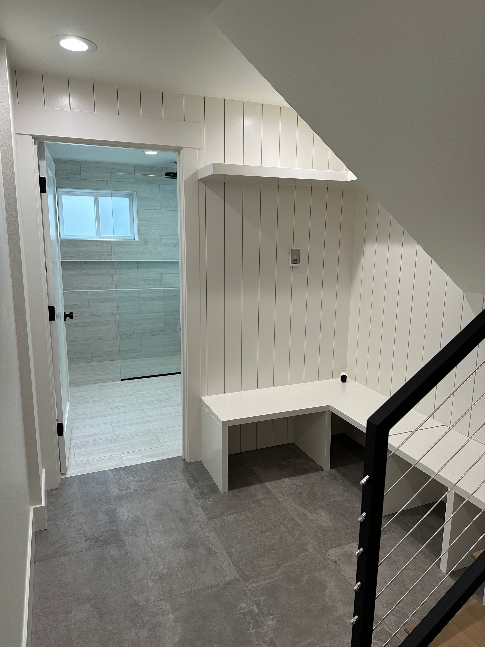 A hallway with a bench and stairs leading to a bathroom
