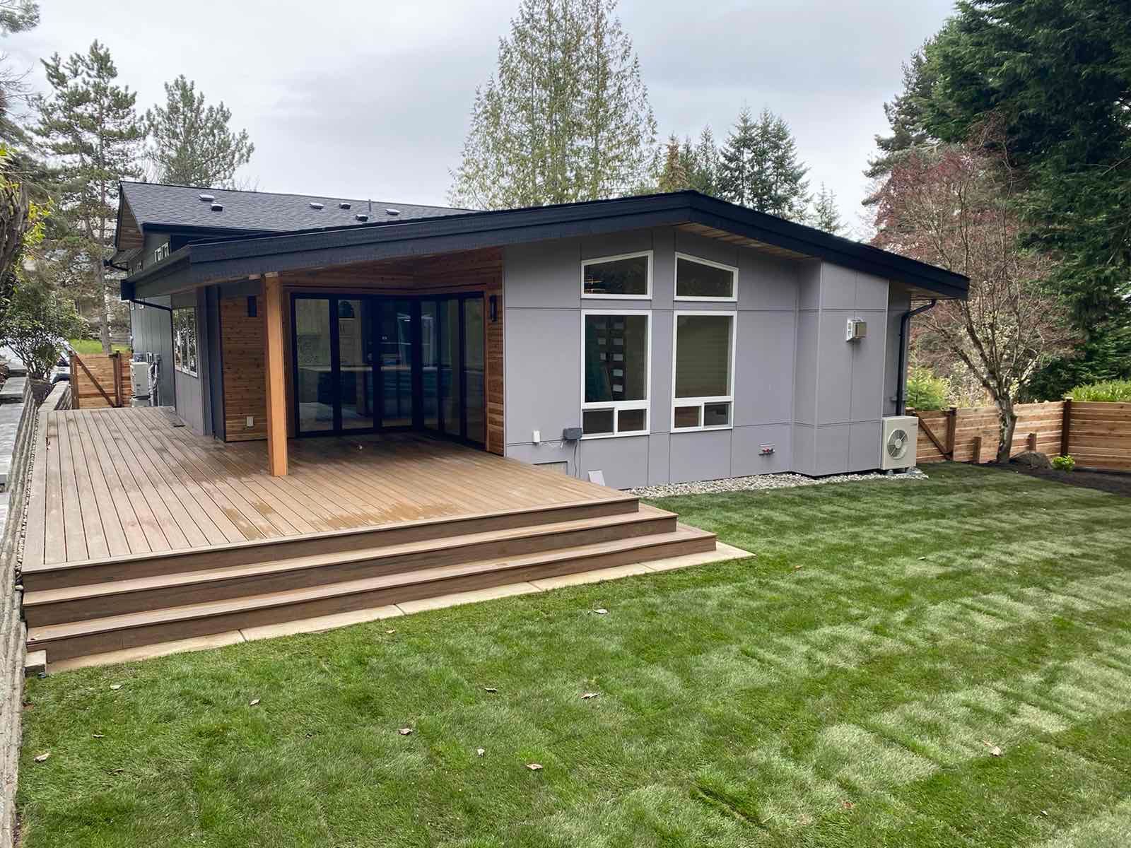 The back of a house with a large lawn and a deck.