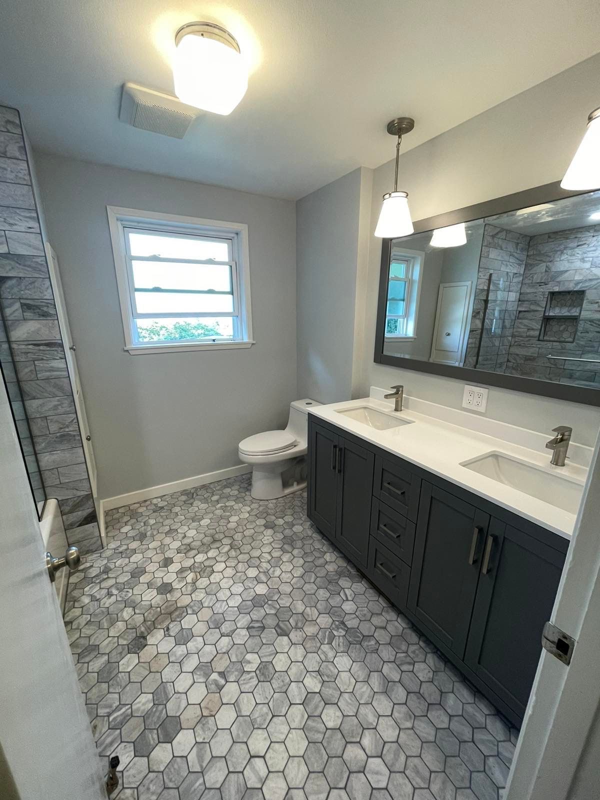 A bathroom with two sinks , a toilet , and a large mirror.