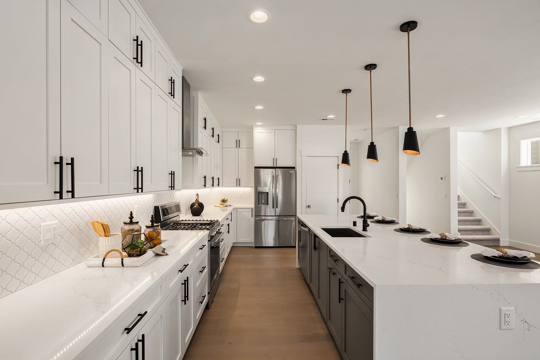 A kitchen with white cabinets , stainless steel appliances , and a large island.