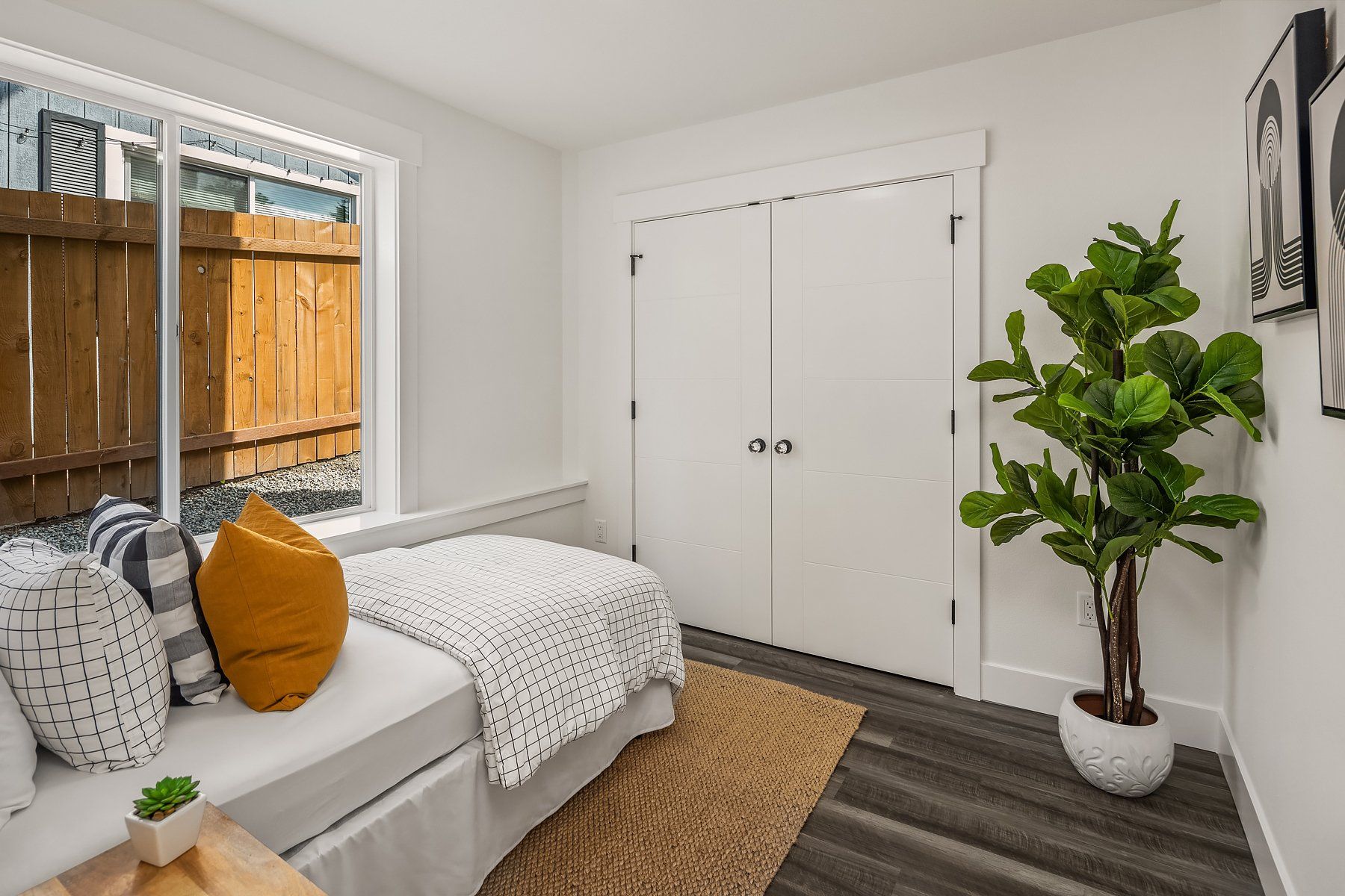 A bedroom with a bed , couch , plant and window.