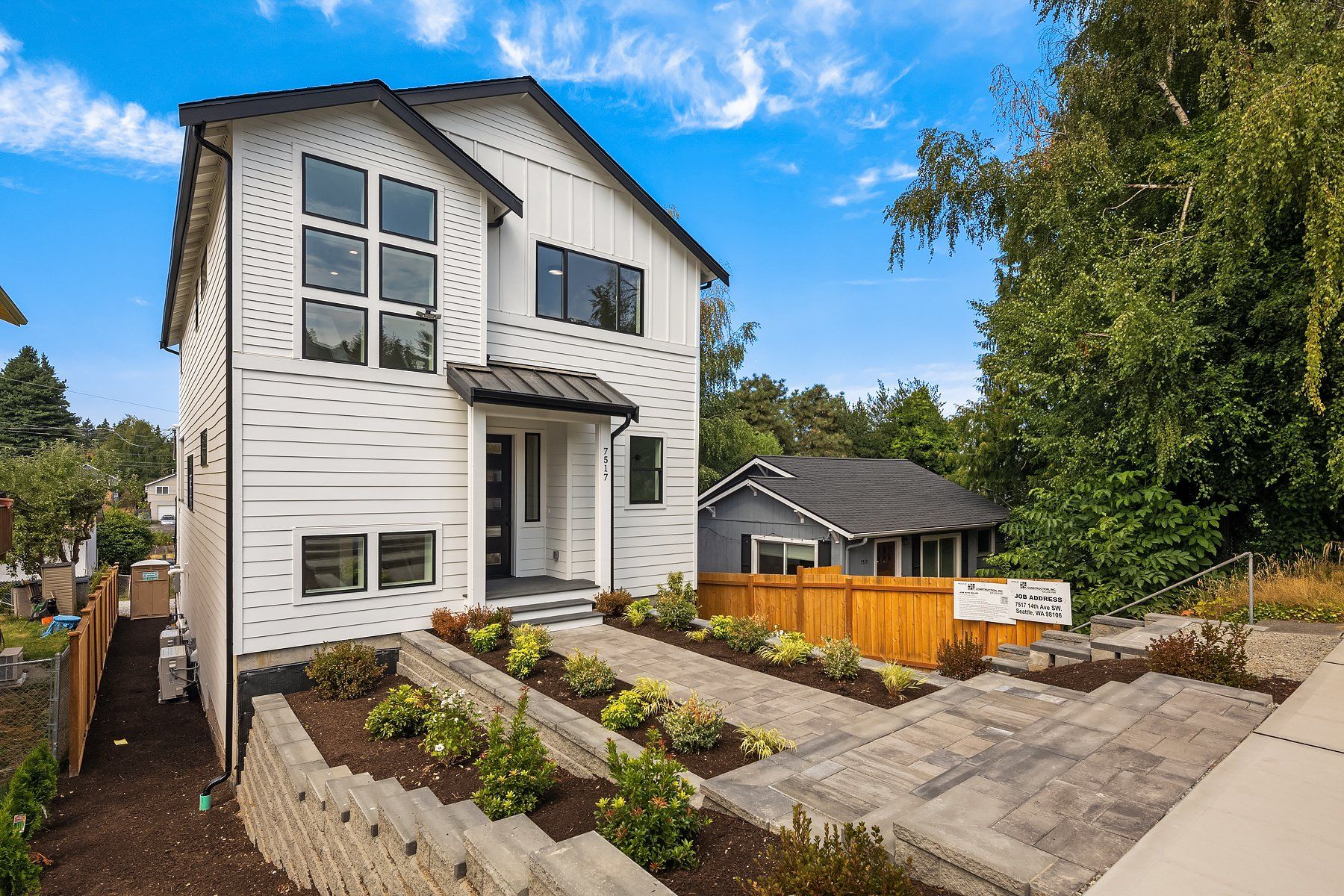 A large white house with a black roof is for sale.