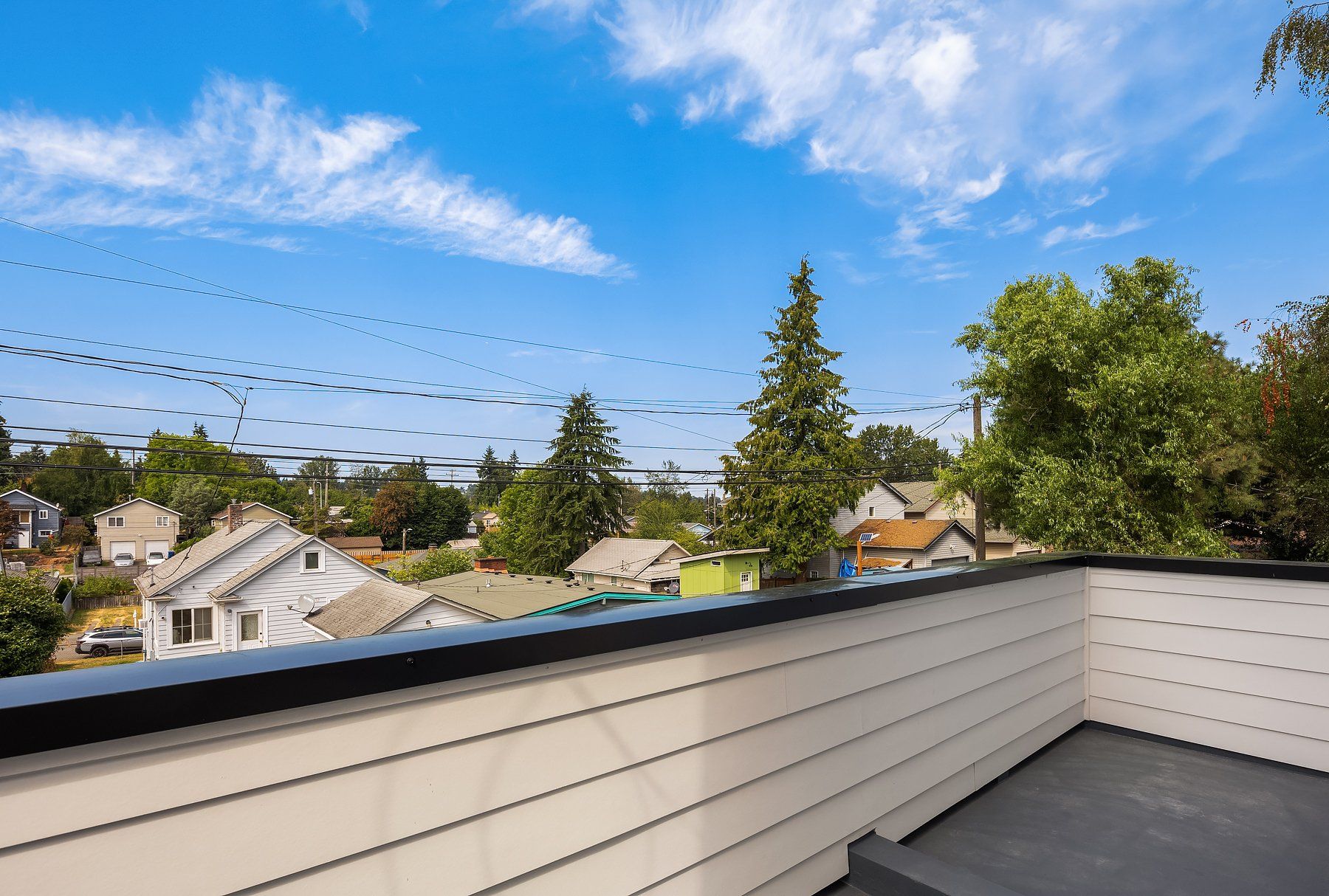 A balcony with a view of a residential area with trees and houses.