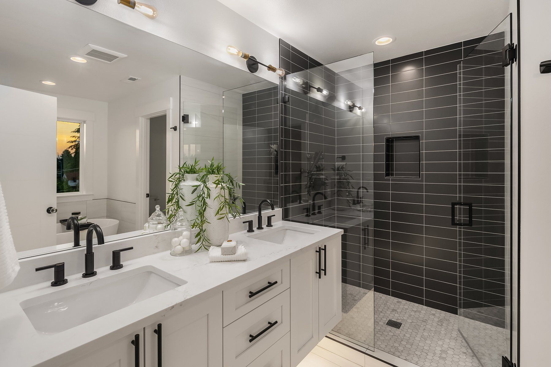 A bathroom with two sinks , a walk in shower and a large mirror.