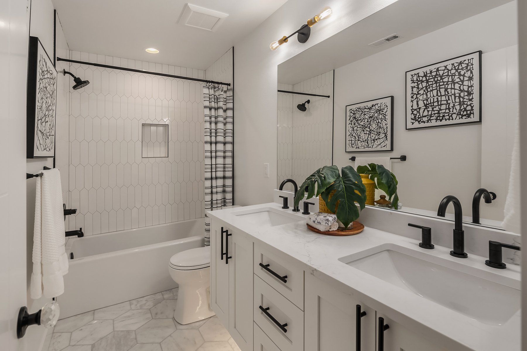 A bathroom with two sinks , a toilet , and a bathtub.