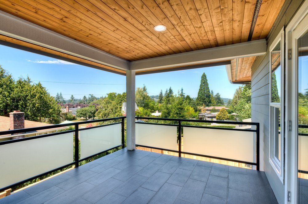 An empty balcony with a wooden ceiling and a glass railing