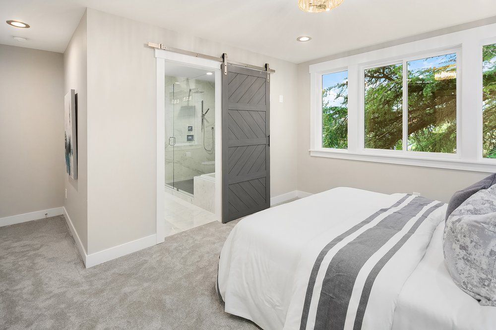 A bedroom with a sliding barn door leading to a bathroom.