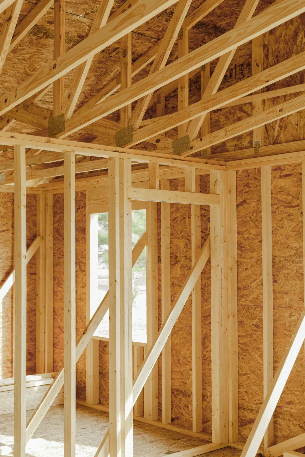 Wooden framing of a house interior under construction; includes studs, rafters, and a window frame.