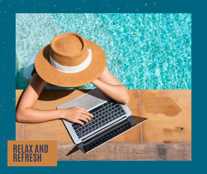 Woman wearing sun hat, working on laptop by pool.