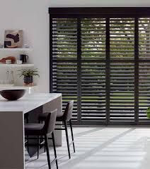 A kitchen with a table and chairs and shutters on the windows.