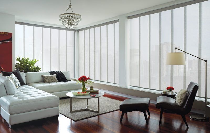 A living room with a white sectional couch , chairs , and a coffee table.