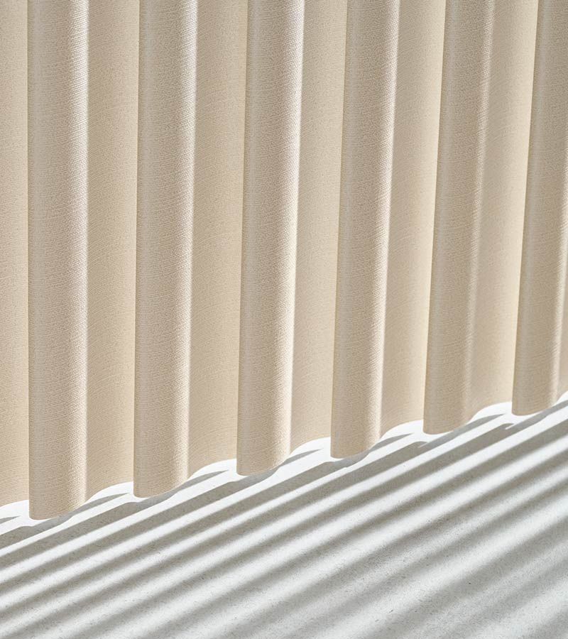 A close up of a white curtain with a shadow on the floor.