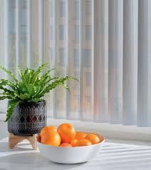 A bowl of oranges is sitting on a table next to a potted plant.