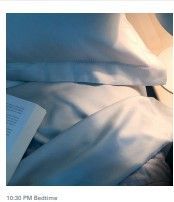 A book is sitting on top of a bed next to a pillow.