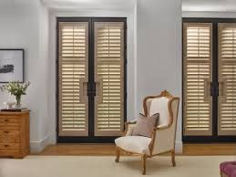 A living room with a chair and shutters on the doors.