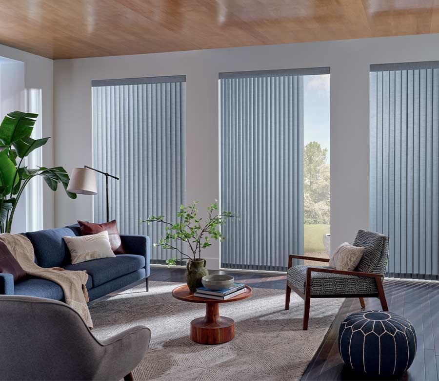 A living room with a couch , chairs , coffee table and vertical blinds.