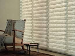 A living room with a chair and a table in front of a window with blinds.